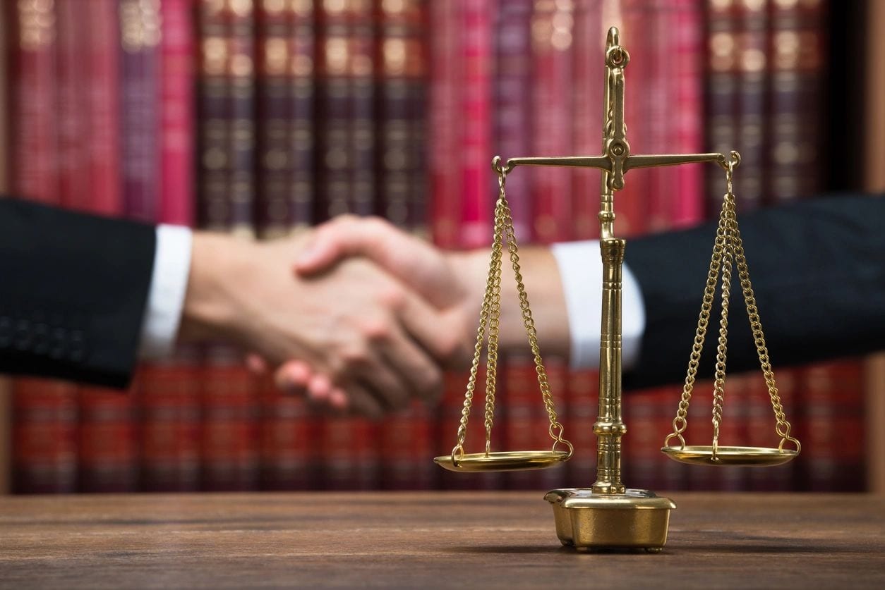 Handshake with legal scales in the foreground.